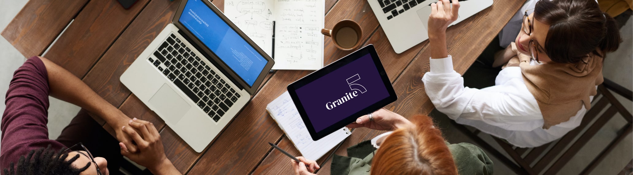 Group of people around a tablet and laptops